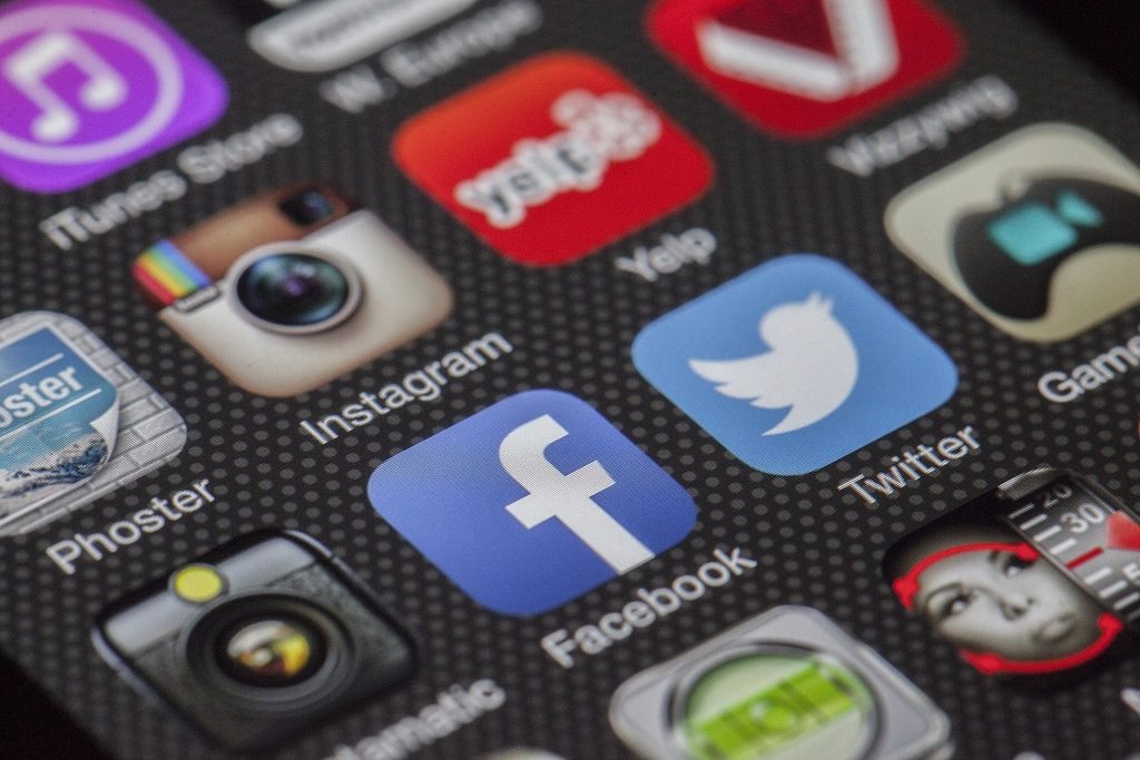 Social media icons and a smartphone in hand